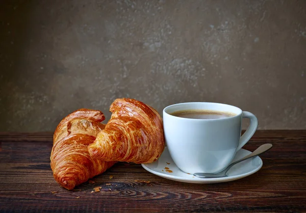 木製のキッチンテーブルの上のコーヒーとクロワッサンのカップ — ストック写真