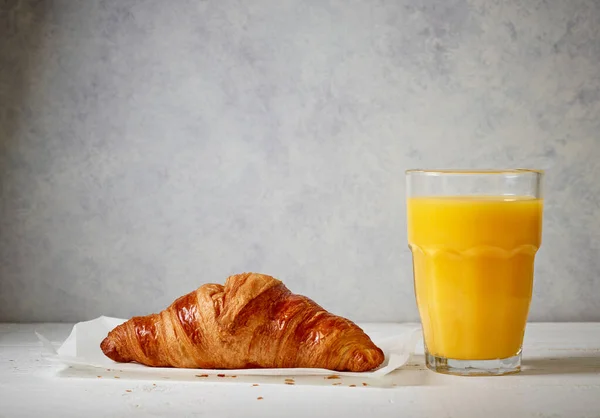Frisch Gebackenes Croissant Und Ein Glas Orangensaft Auf Dem Küchentisch — Stockfoto
