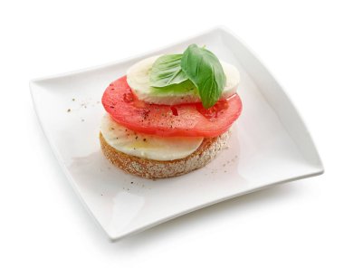 Beyaz arka planda domates ve mozzarella ile izole edilmiş bir tabak bruschetta.