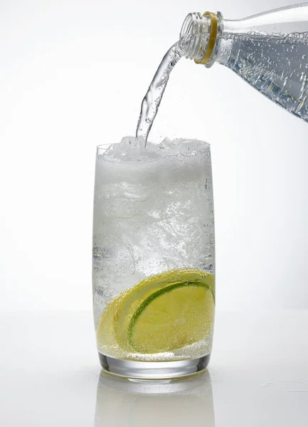 Agua Vertiendo Vaso Hielo Rodajas Limón Sobre Fondo Blanco —  Fotos de Stock