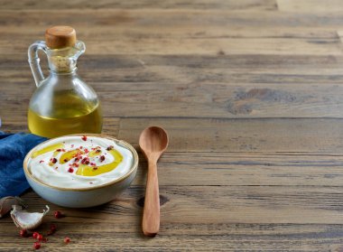 bowl of sour cream or greek yogurt decorated with olive oil and red pepper on wooden kitchen table