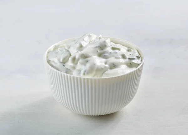 bowl of sour cream or greek yogurt tzatziki sauce on white kitchen table