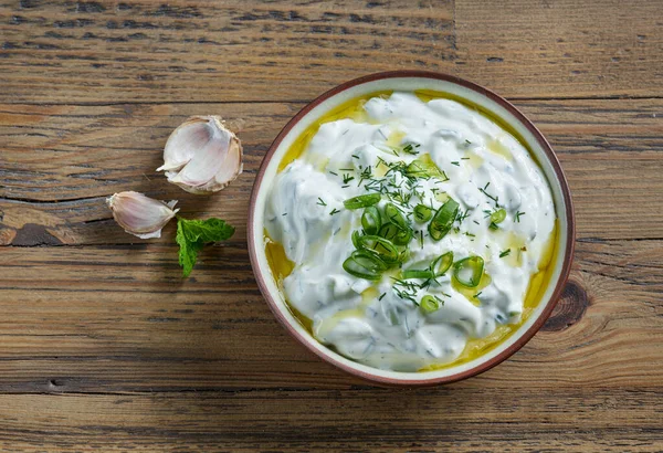 bowl of sour cream or greek yogurt sauce tzatziki on wooden kitchen table, top view