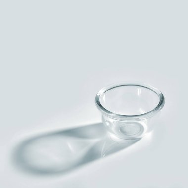 empty glass bowl with long shadow on white background