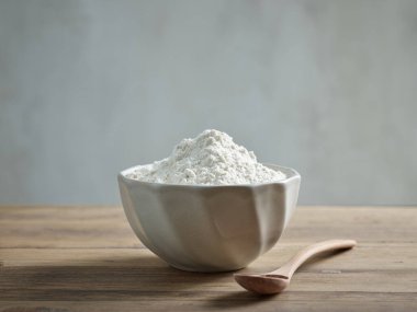 ceramic bowl of flour and spoon on wooden kitchen table