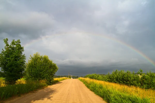 Landweg en regenboog — Stockfoto