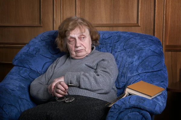 De grootmoeder in een fauteuil met het boek — Stockfoto