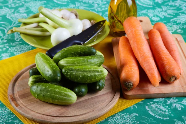 Green cucumbers with onions garlic and carrots on a kitchen tabl — Stock Photo, Image