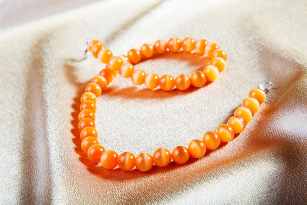 Yellow beads on a golden fabric — Stock Photo, Image