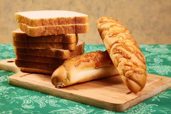 Stukken van brood en roll op een keukentafel — Stockfoto