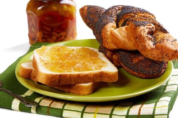 Pezzi di pane con marmellata e rotoli su un tavolo da cucina — Foto Stock