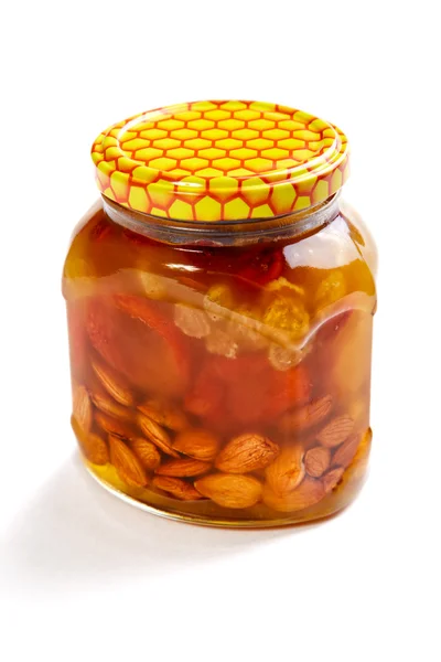 Bank of honey with the candied fruit and nuts on a white backgro — Stock Photo, Image