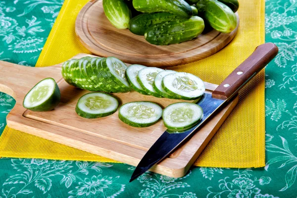 De gesneden groene komkommers en mes op een keukentafel — Stockfoto