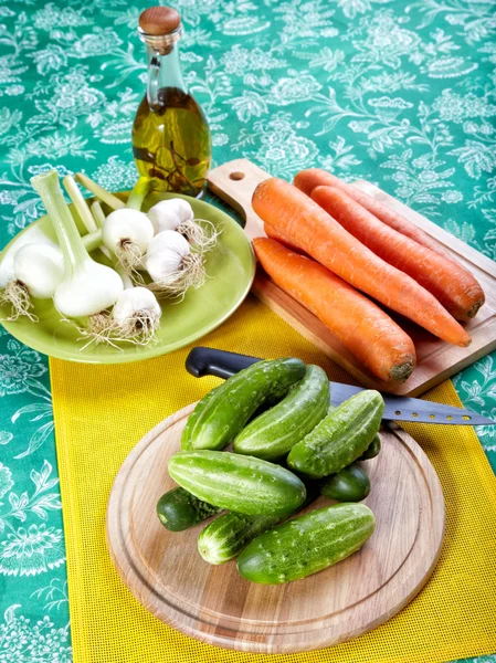 Green cucumbers with onions garlic and carrots on a kitchen tabl — Stock Photo, Image