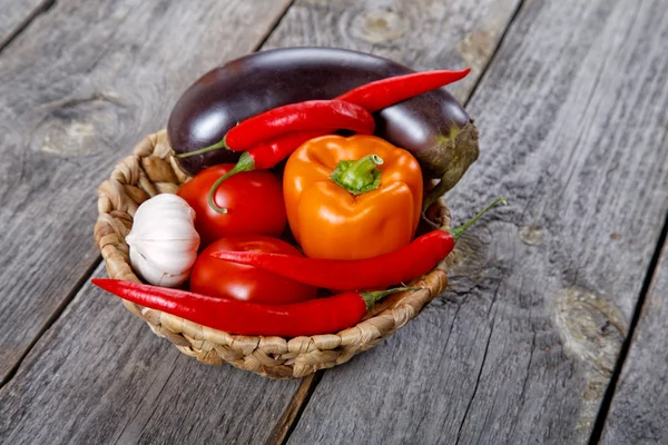 Wattled basket with vegetables on an old table — Stock Photo, Image