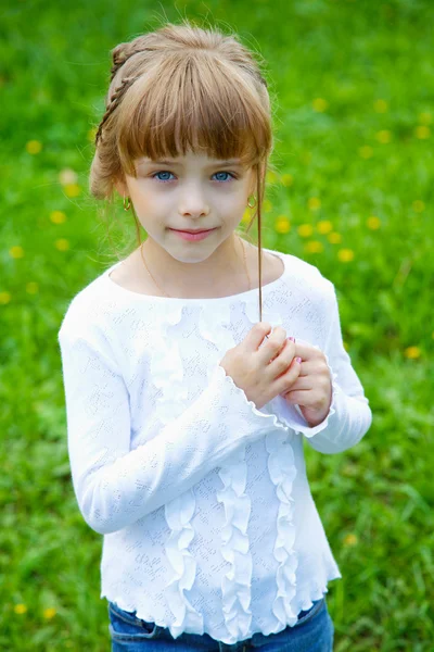 Bambina contro un'erba verde in primavera — Foto Stock