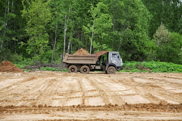 Autocarro con cassone ribaltabile scarica un terreno sul terreno — Foto Stock