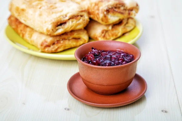 Cup with jam and sweet rolls on a table — Stock Photo, Image