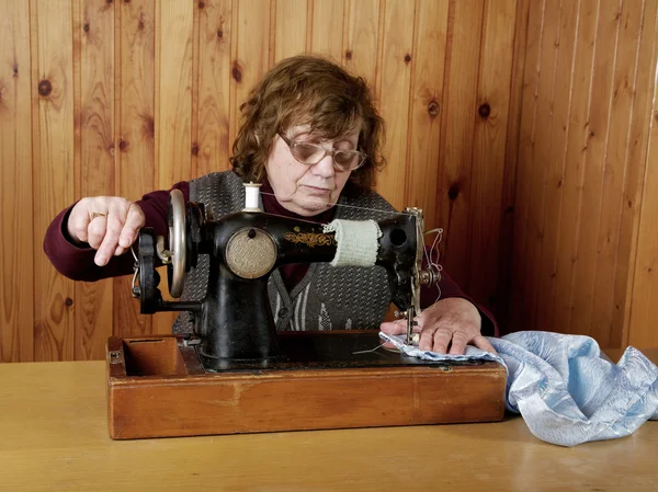 De oude vrouw naait op de naaimachine — Stockfoto