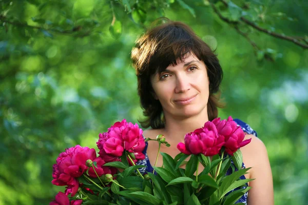 Kvinna i en trädgård med massa blommor mjukt fokus — Stockfoto