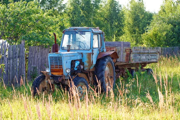 Tractor de ruedas viejo con el remolque contra madera —  Fotos de Stock