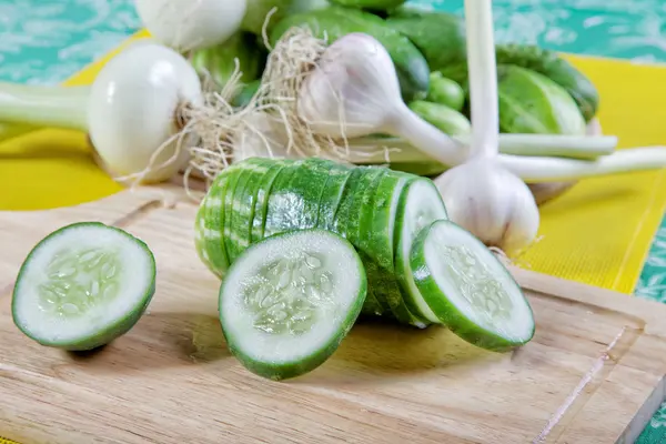 Still-life with the cut cucumbers an onions and garlic — Stock Photo, Image