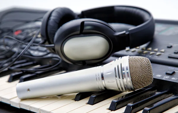 Microphone and ear-phones lie on the keyboard — Stock Photo, Image