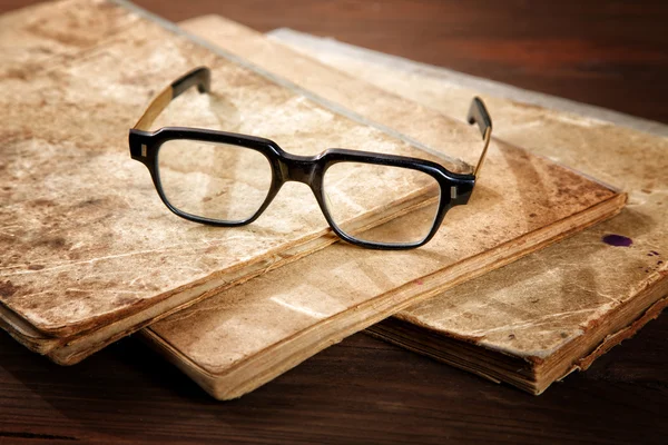 Gamle skrivebøger og briller på et træbord - Stock-foto