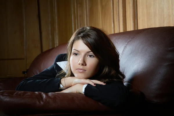 Retrato de la chica pensativa en un sofá de cuero — Foto de Stock