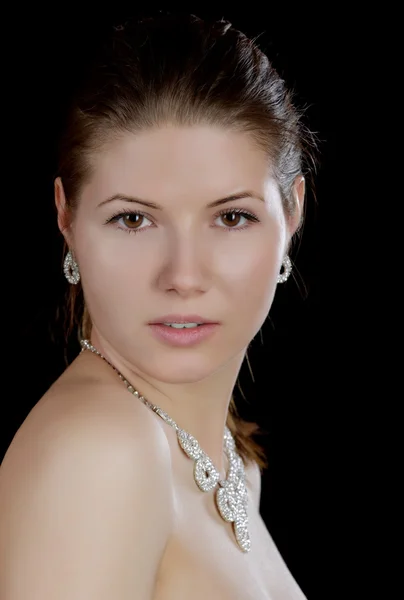 The girl in  necklace with naked shoulders on a black background — Stock Photo, Image