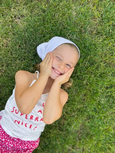 Mutlu Küçük Bir Kız Yeşil Çimlerin Üzerinde Yatıyor — Stok fotoğraf