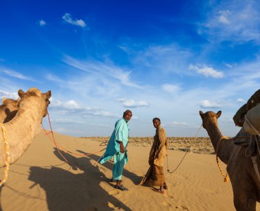 Two cameleers (camel drivers) with camels in dunes of Thar deser clipart