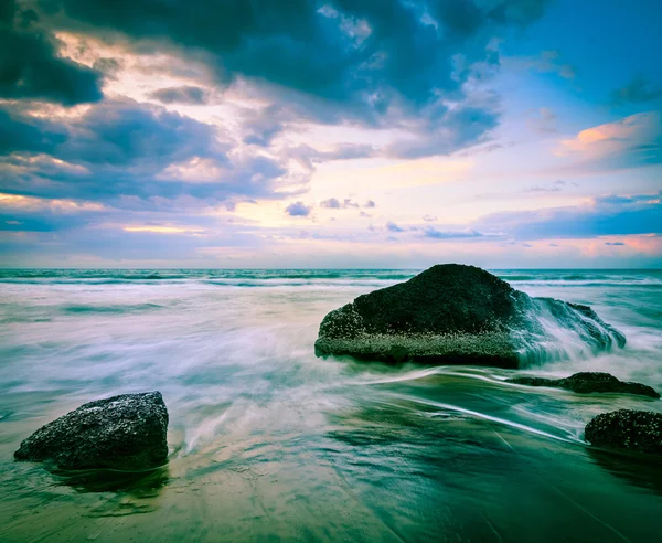 Fale i skały na plaży o zachodzie słońca — Zdjęcie stockowe