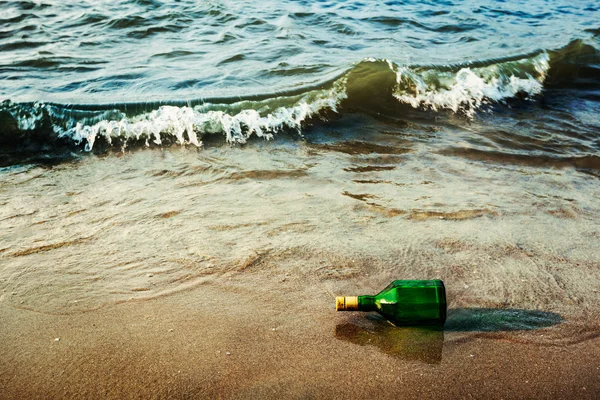 Бутылка для сообщений на пляже волнами — стоковое фото