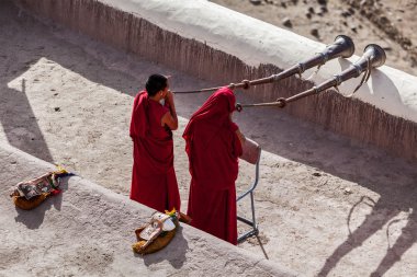 Two Tibetan Buddhist monks blowing Tibetan horn (dungche) clipart