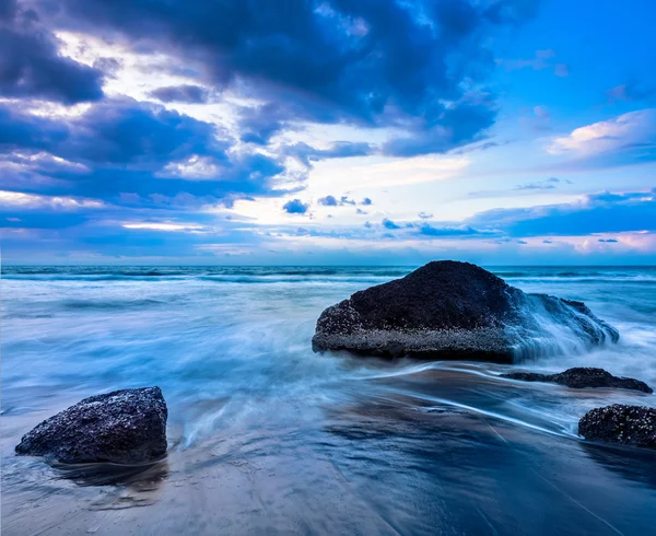 Wellen und Felsen am Strand des Sonnenuntergangs — Stockfoto