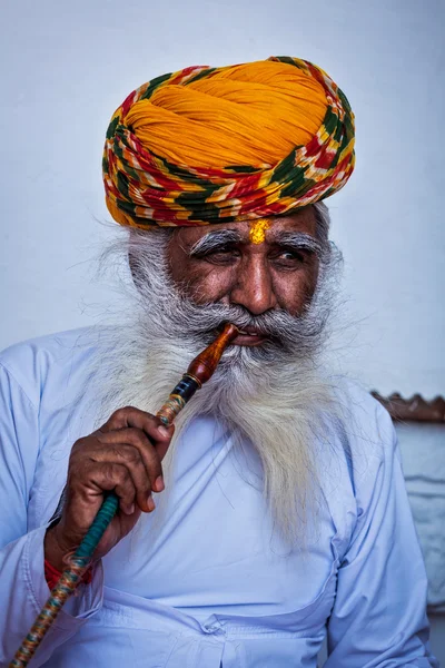 Old Indian man smokes hookah (waterpipe) in Mehrangarh fort — Stock Photo, Image