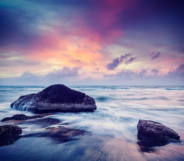 Wellen und Felsen am Strand des Sonnenuntergangs — Stockfoto