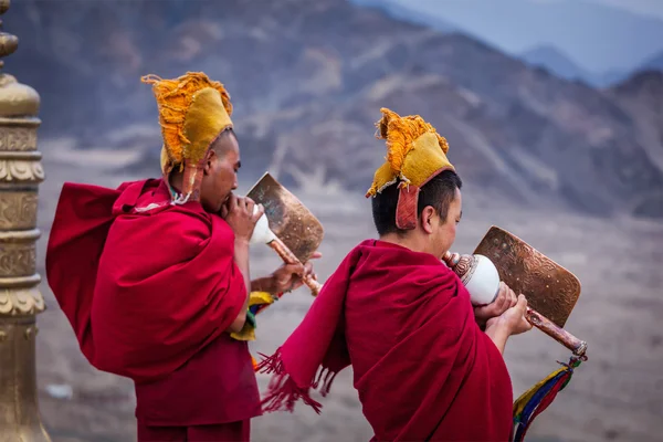 Två tibetanska buddhistmunkar blåser conches under morgonen pooja — Stockfoto