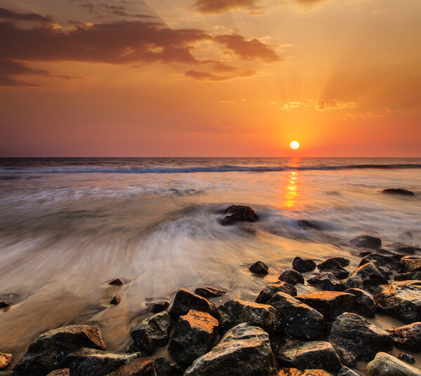 Waves and rocks on beach of sunset