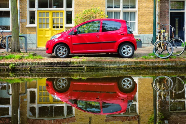 델프트 거리에 있는 운하 둑에 있는 빨간 자동차에요. 델프트, 네덜란드 — 스톡 사진