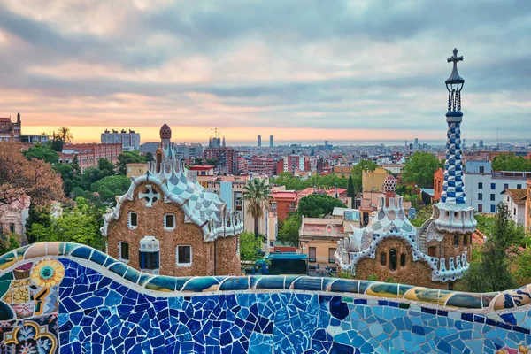 Uitzicht op de stad Barcelona vanaf Guell Park. Zonsopgang uitzicht op kleurrijke mozaïek gebouw in Park Guell — Stockfoto