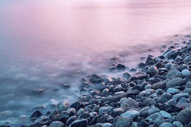 Deniz kıyıları, kayalar ve dalgalarla dolu rüya gibi doğal bir arka plan. Uzun pozlama