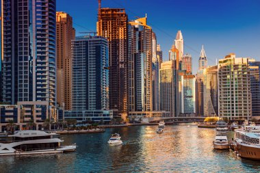 Gün batımından önce Dubai Marina 'da gökdelenler, botlar ve deniz yansımaları, Birleşik Arap Emirlikleri