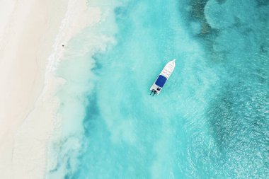 Saona adasındaki güzel Karayip plajı, Dominik Cumhuriyeti. Mavi deniz suyu, beyaz kum ve tek bir tekneyle tropikal sakin yaz manzarasının havadan soyut görüntüsü.
