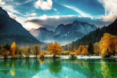 Güneşin doğuşundaki Triglav dağı tepesi Jasna Gölü 'ne yansıdı. Sabah ışığında bulutlar güzeldi. Slovenya, Triglav Ulusal Parkı