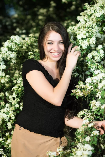 Jonge brunette in de bloeiende struiken — Stockfoto