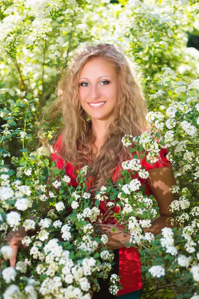 Blonde vrouw poseren in de buurt van bloeiende bush — Stockfoto