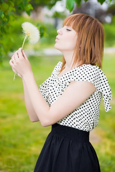 Redhead woman blowing dandelion — Stock Photo, Image