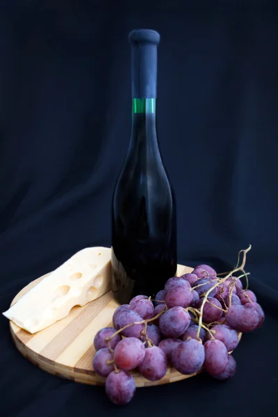 Garrafa de vinho, uvas e queijo no tabuleiro — Fotografia de Stock